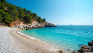 Sheltered pebble cove with calm turquoise water on a Greek island, with the open sea beyond the headland